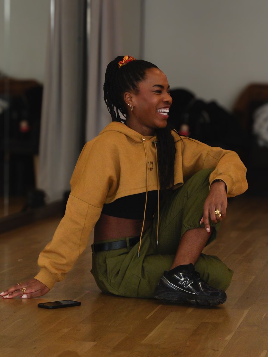 Danseuse souriante assise sur le parquet du studio The Muse Lab